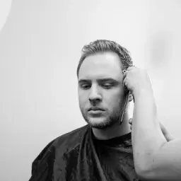 Un uomo con barba e basette viene tagliato. Diverse tipi di basette sono possibili, ma queste sono in fase di definizione.
