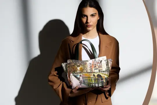 Modella con un cappotto marrone tiene una borsa Y Not con stampa di Amsterdam.